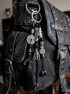 Yin Talisman Snake Bone Keychain, snake bone and coin keychain hanging from the strap of a black leather bag