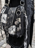 Yin Talisman Snake Bone Keychain, black tassel and coin charm keychain clipped to a patterned gothic-style bag