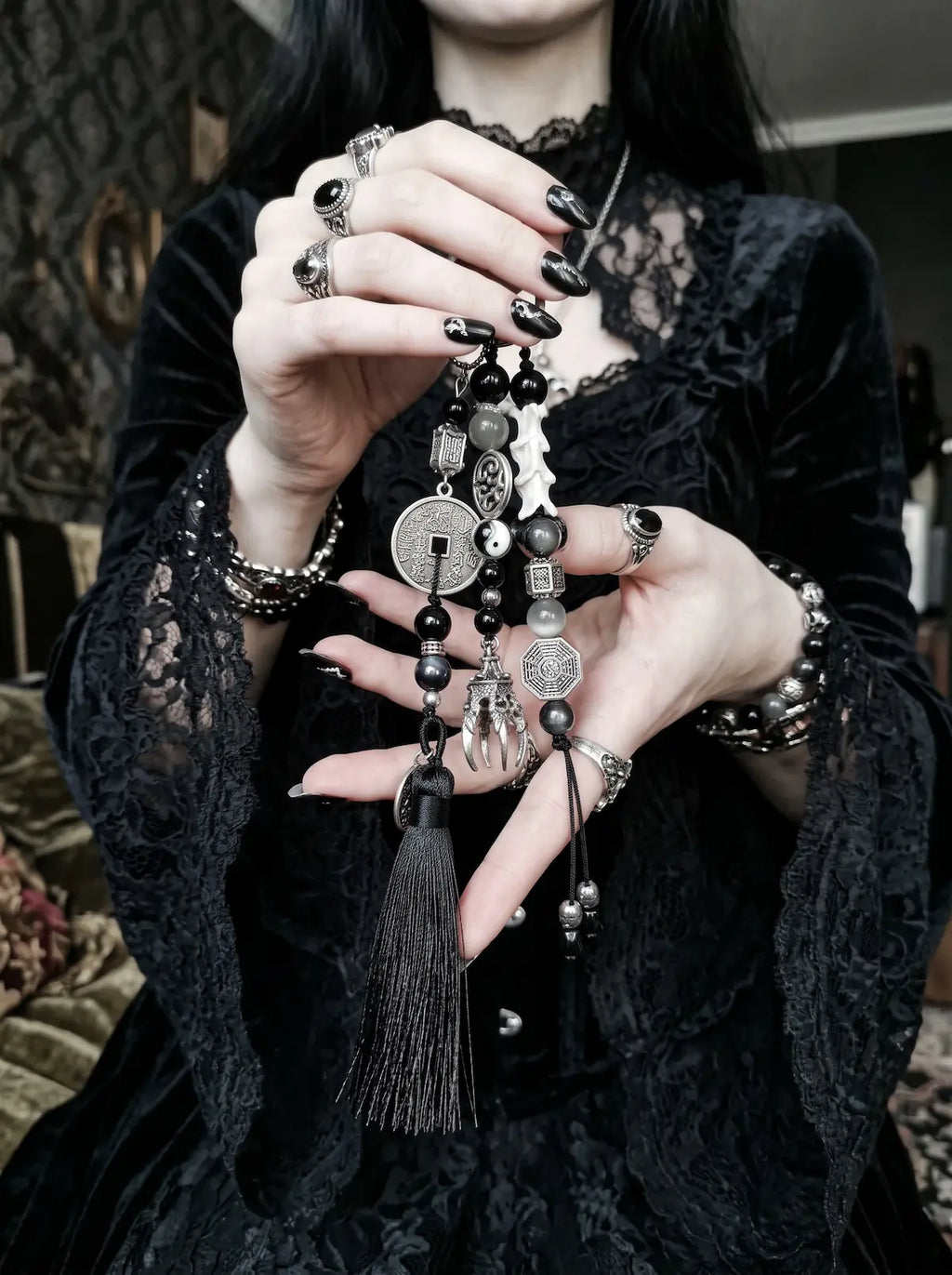 Yin Talisman Snake Bone Keychain, model holding the black tassel and mixed metal talisman keychain in both hands