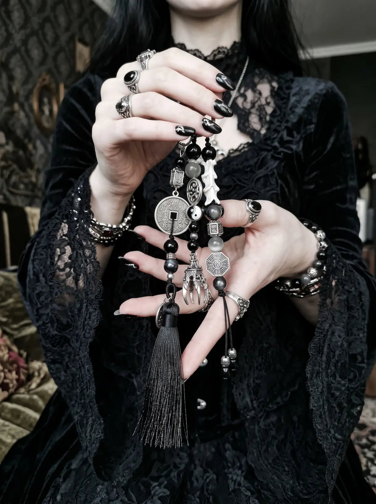 Yin Talisman Snake Bone Keychain, model holding the black tassel and mixed metal talisman keychain in both hands