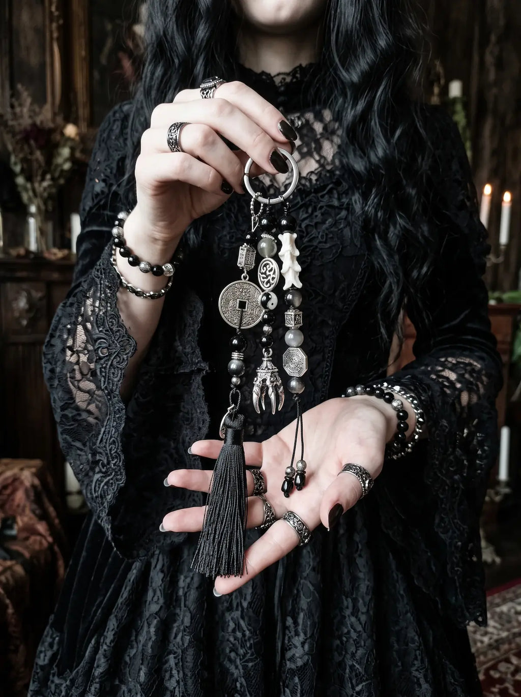 Yin Talisman Snake Bone Keychain, full view of long black tassel keychain with snake bone and metal charms in hand
