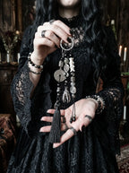 Yin Talisman Snake Bone Keychain, full view of long black tassel keychain with snake bone and metal charms in hand