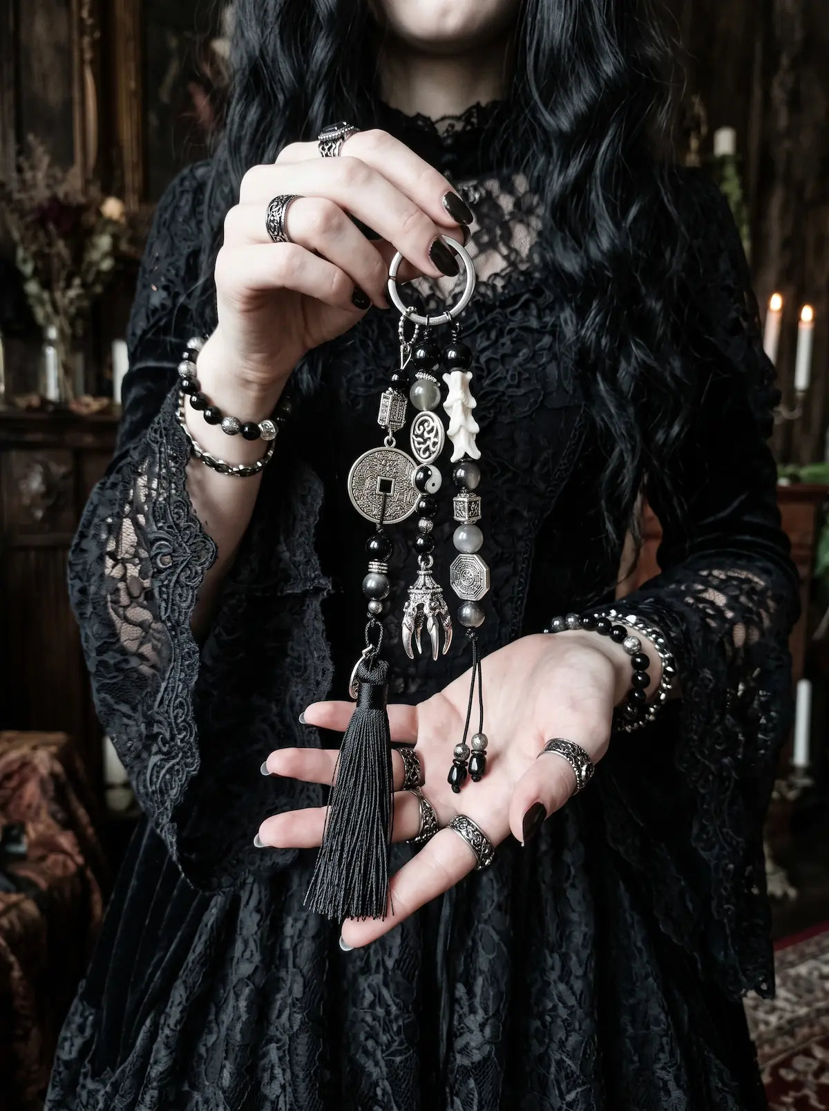 Yin Talisman Snake Bone Keychain, full view of long black tassel keychain with snake bone and metal charms in hand